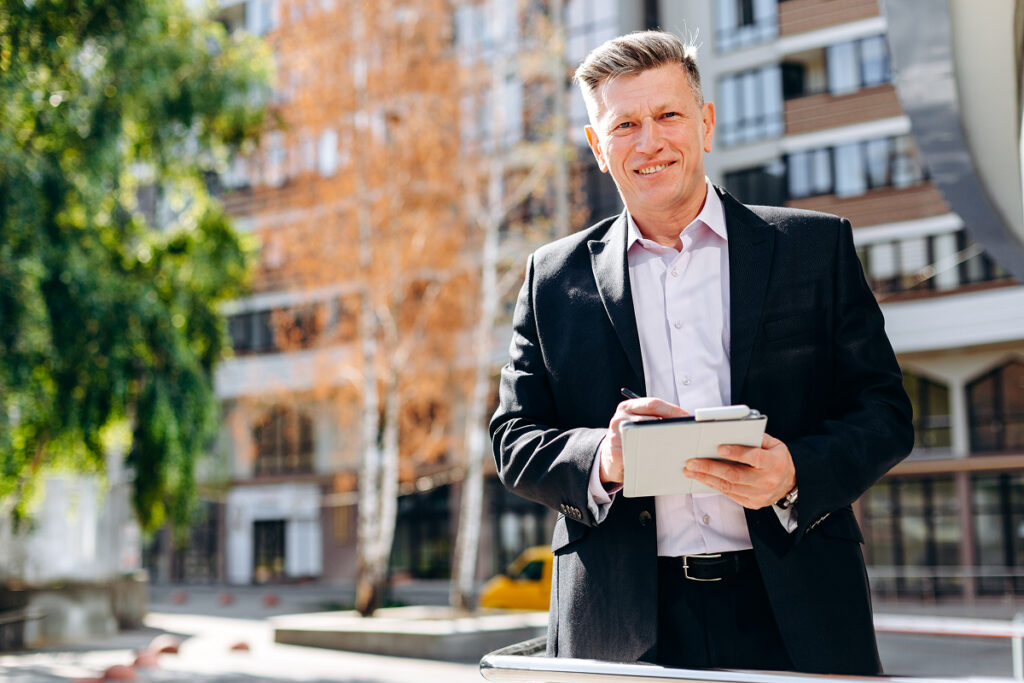Senior businessman outside writing a note